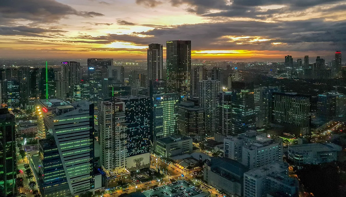 Bonifacio Global City skyline at dusk with lit towers under an orange sunset sky, Taguig, Metro Manila