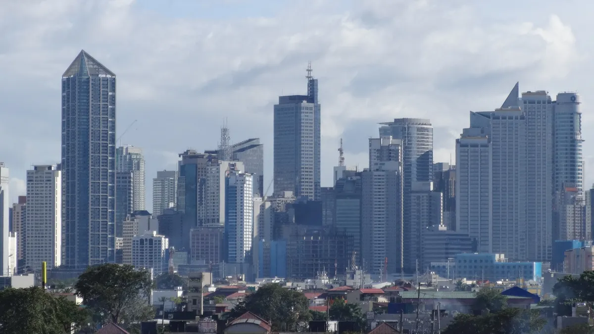 Makati central business district skyline with high-rise condo and office towers under a partly cloudy sky