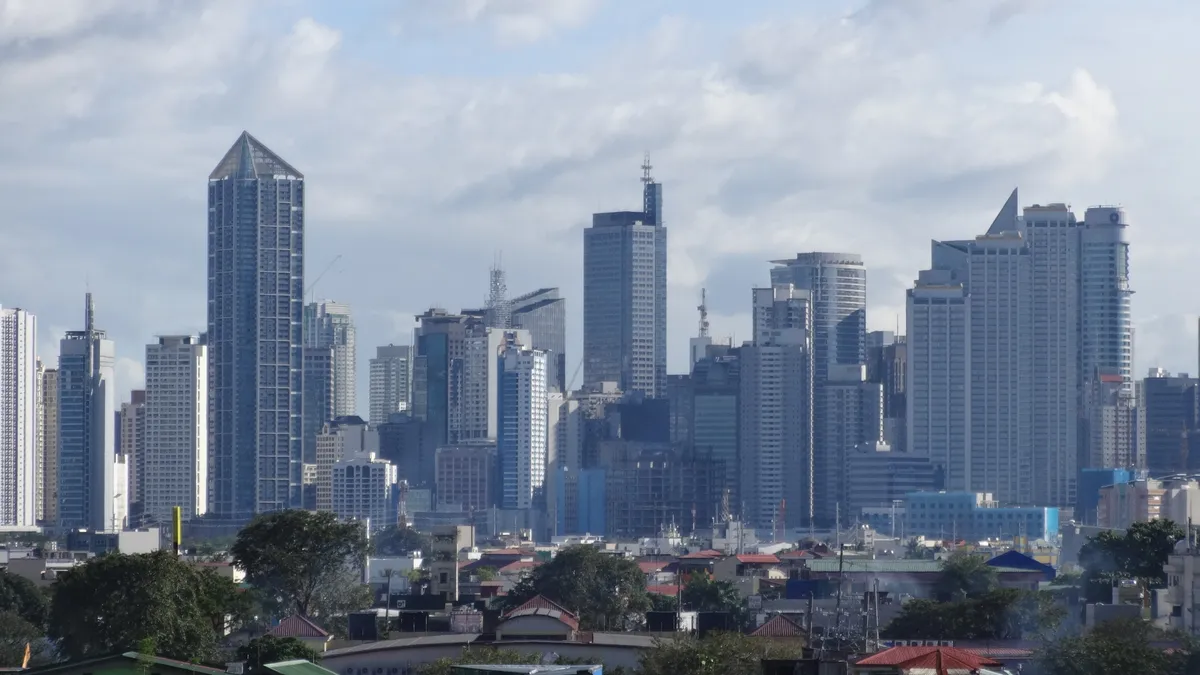 Makati central business district skyline of tall residential and office towers against a cloudy blue sky